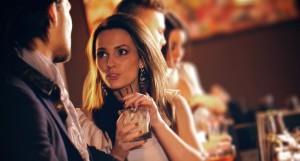 Young woman with a glass of wine talking to a man at the bar
